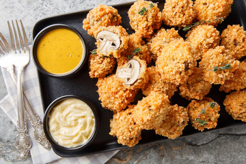 Crispy fried cremini mushrooms in panko breading close-up in a plate on the table. Horizontal top view from above