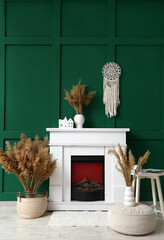 Fototapeta premium Fireplace and pampas grass in vases near green wall in room