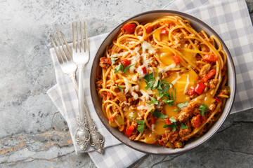 One pot Taco Pasta with ground beef, green chili, onion, cheese, tomatoes, spices close-up in a plate on the table. Horizontal closeup on the plate on the table. Horizontal top view from above