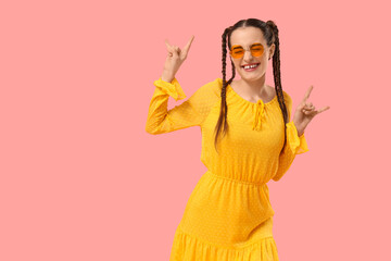 Happy young woman with braids dancing and showing 