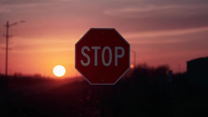 Framing centered red octagon STOP sign glowing as low sun emerging over roadside, with utility pole - Powered by Adobe