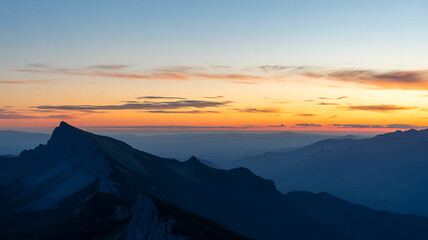 Dramatic mountain peaks silhouetted against a vibrant, colorful sunset sky with warm hues