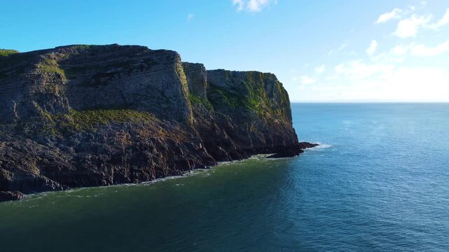 Slow Aerial of Seascape with Steep Rugged Cliffs with Calm Ocean. Travel Nature Drone Clip. Beautiful Welsh Gower Peninsula Coast.