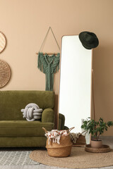 Obraz premium Interior of living room with green sofa, mirror, home decor and houseplant near beige wall