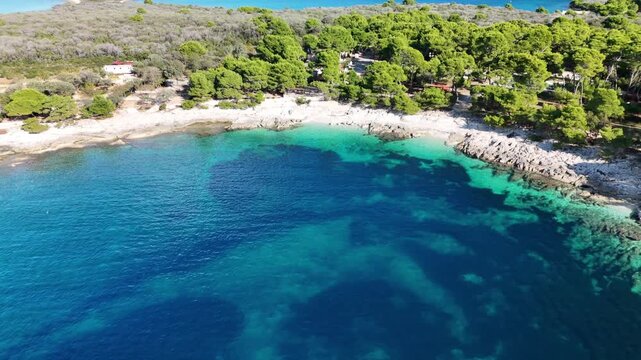 Wide drone panorama over a turquoise cove and pine forest on Dugi Otok, Croatia. Camera lifts to reveal the island&rsquo;s scenic coastline and natural beauty.