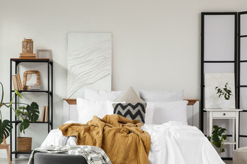 Interior of light bedroom with folding screen, bookshelf and table