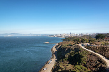 Obraz premium Cityscape of San Francisco, California, with Alcatraz Island visible in the distance across the bay under clear daylight conditions.