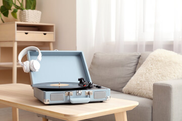 Retro record player with headphones and vinyl disk on coffee table in living room, closeup