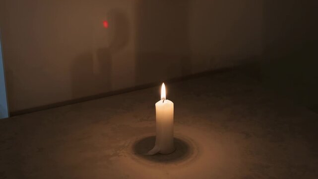 Appearing red dot drawing silhouette aiming pointer while candle forming wax ring in dim room