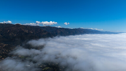 Aerial view of the serene landscape where the rugged mountain peaks meet the soft, rolling clouds, a dance of earth and sky in harmonious contrast, Montecito, California, United States.