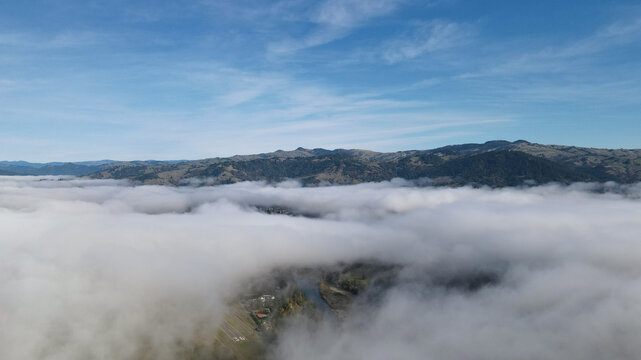 Aerial view of a sea of clouds blanketing the landscape, with mountain ridges piercing through the dense fog, Miranda, California, United States.