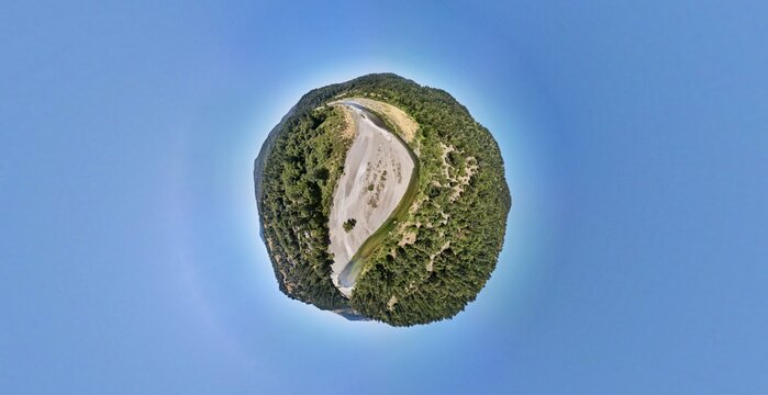 Aerial view of a tiny planet displaying a stark contrast between the lush, verdant forest and the pale, sandy riverbed winding through, Miranda, California, United States.