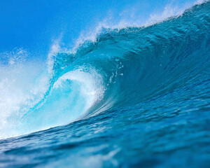 Massive blue ocean wave curling, bright turquoise barrel breaking with foamy crest and spray, sunlight