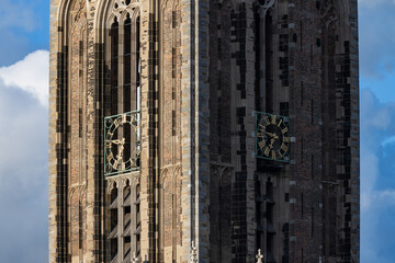 Close-up detail of the golden clock face and Gothic brickwork on the medieval Dom Tower in Utrecht, Netherlands, on a sunny day.