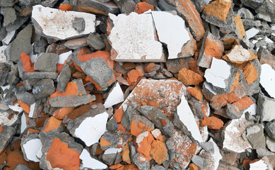 A pile of broken construction debris with mixed materials such as concrete, bricks, and plaster fragments. Rough texture rubble background for industrial, demolition, and recycling themes