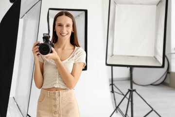 Young female photographer with camera during courses in studio
