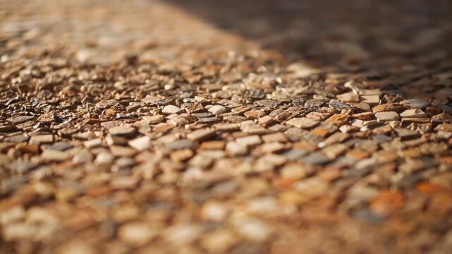 Shifting camera advancing refocusing on mosaic pavement in plaza, showing pebble texture, sunlight