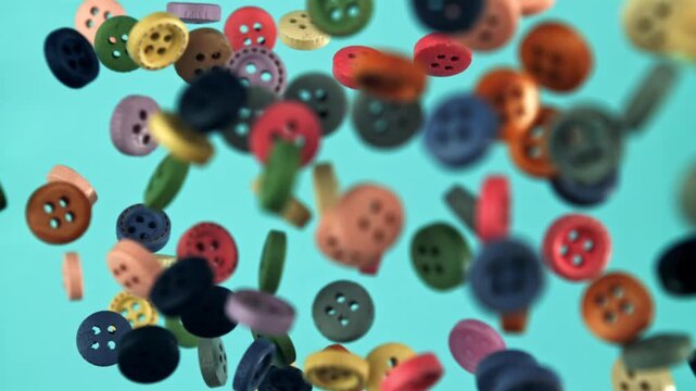 Multi-colored buttons fly on a blue background. Filmed on a high-speed camera at 1000 fps. High quality FullHD footage