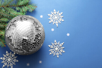 Composition with disco ball, Christmas decor and fir tree branch on blue background, closeup