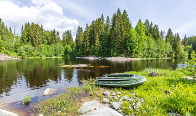 Green boat is sitting on the grass next to a lake