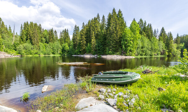 Green boat is sitting on the grass next to a lake - Powered by Adobe