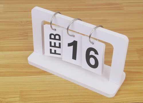 February, 16 on calendar on wooden table close-up.	