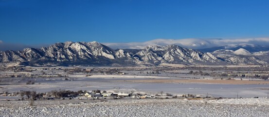 the  striking boulder flatirons and  snow -capped peaks of the front range of the colorado rocky mountains in winter as seen from broomfield, colorado, in early morning © Nina