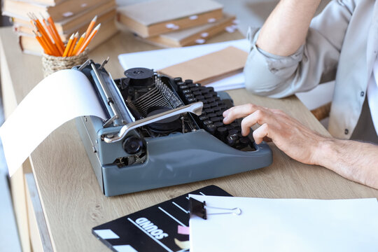 Male screenwriter using typewriter at table in office, closeup