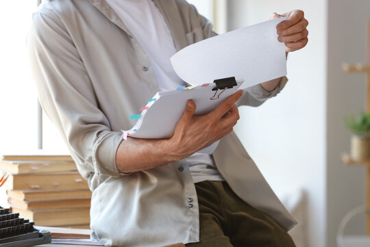 Male screenwriter reading script in office