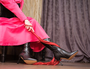 women's legs in high-heeled boots and a whip in their hands