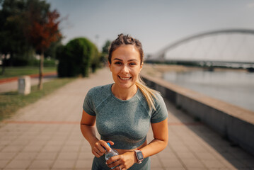Sporty woman holding water bottle after running in city park