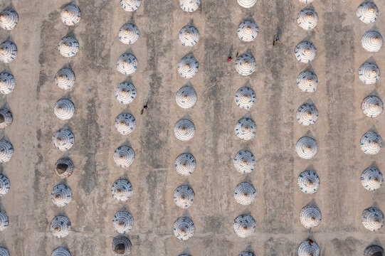 Aerial view of numerous white objects, possibly haystacks or similar agricultural products, arranged in neat rows across a vast field, Bhairab, Dhaka Division, Bangladesh.