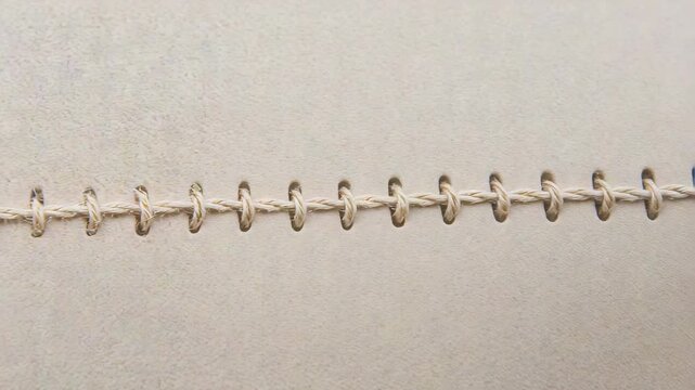 Sliding camera revealing horizontal stitched seam in studio, showcasing even looped beige thread