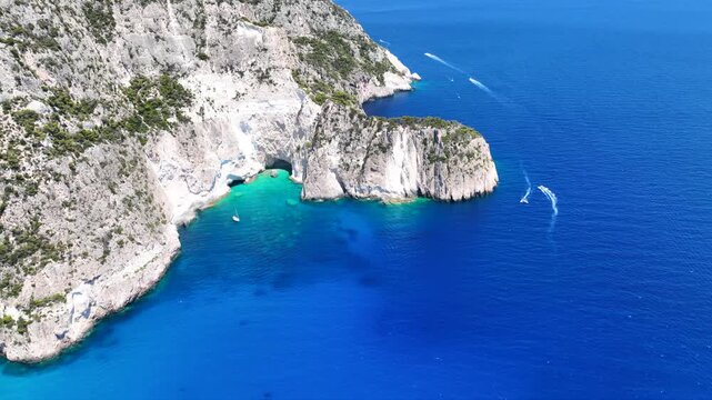 Aerial drone cinematic video of limestone white cliffs surrounded by deep blue emerald crystal clear sea and sea caves creating a true paradise for yachts and sailboats in tropical exotic island bay