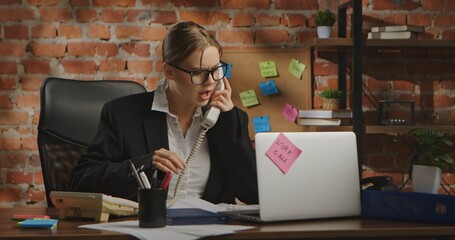 A woman in a business suit talks on two phones at the same time