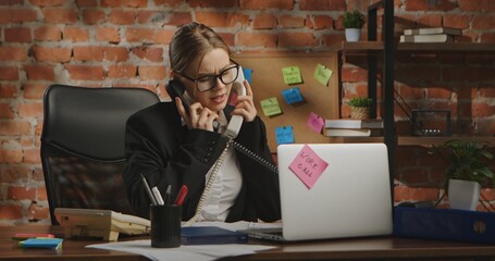 A woman in a business suit talks on two phones at the same time