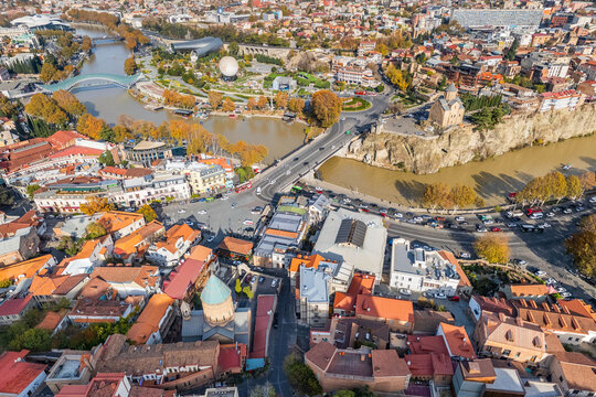 Aerial view of the Peace Bridge arching over the Mtkvari River, framed by the ancient Narikala Fortress and the modern Rike Park, Tbilisi, Tbilisi, Georgia.