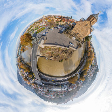 Aerial view of the Metekhi Church standing proudly over the Kura River, a bridge arching gracefully across its waters, Tbilisi, Tbilisi, Georgia.