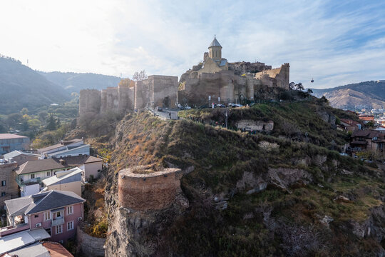 Aerial view of Narikala Fortress perched atop a hill, its ancient stone walls glowing under the sun, overlooking the city, Tbilisi, Tbilisi, Georgia.