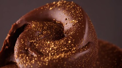 Panning camera revealing dark chocolate swirl in studio to show surface detail and gold flakes - Powered by Adobe