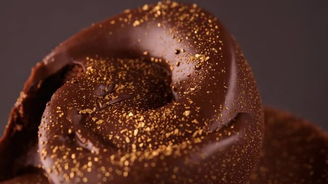 Panning camera revealing dark chocolate swirl in studio to show surface detail and gold flakes