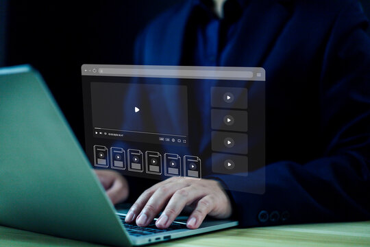 A professional using a laptop with a futuristic digital interface displaying video files and media options, representing concepts of online streaming, data management, and modern digital workflow.