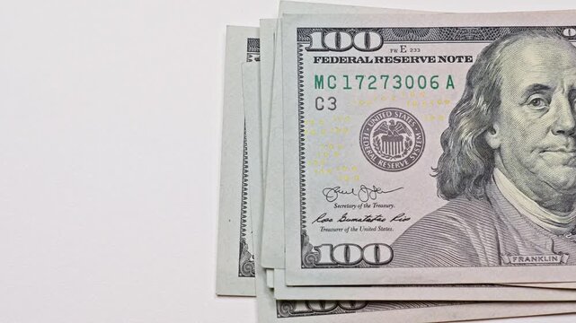 Stack of US hundred dollar bills being counted on a light table with copy space, illustrating cash pile, financial calculations, cash flow, and banking concepts.