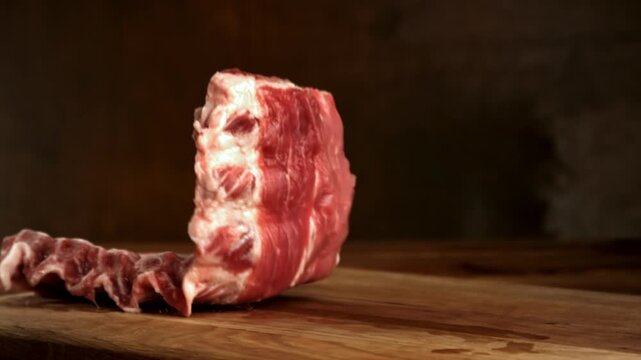 Raw pork ribs fall onto a cutting board. Filmed on a high-speed camera at 1000 fps. High quality FullHD footage