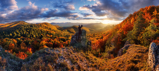 Fototapeta premium Scenic autumn sunset panorama in Strazovske vrchy in Slovakia with dramatic sunlight clouds on sky on colorful leaves on trees in forests on stone and rocky hills and valley mountain.