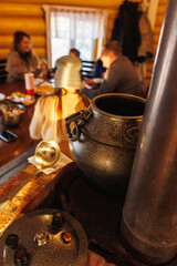 CastIron Pot Steaming On Table Foreground Blurred Diners Around Wooden Table Warm Candlelight Snowy Window