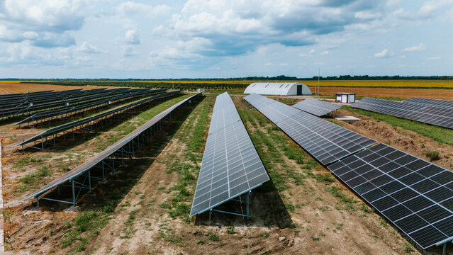 Aerial view of rows of solar panels stretch across the landscape under a sky dotted with fluffy clouds, creating a stark contrast between technology and nature, Belgrade, City of Belgrade, Serbia.