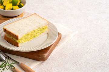 Healthy avocado and egg salad sandwich on white plate for breakfast