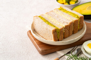 Healthy avocado and egg salad sandwich on white plate for breakfast