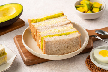 Healthy avocado and egg salad sandwich on white plate for breakfast